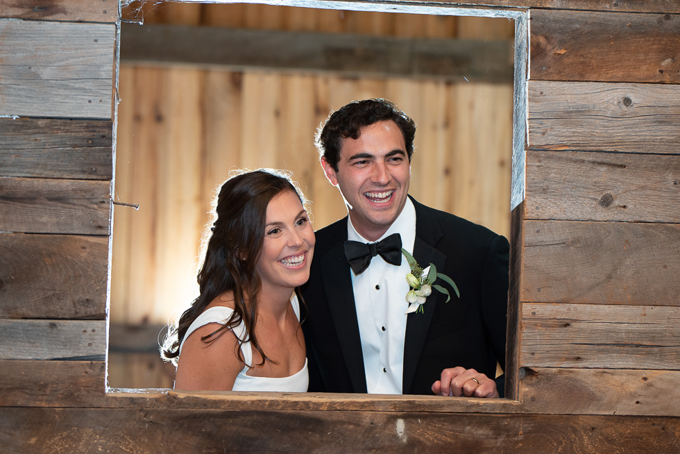 bride & groom looking through barn window