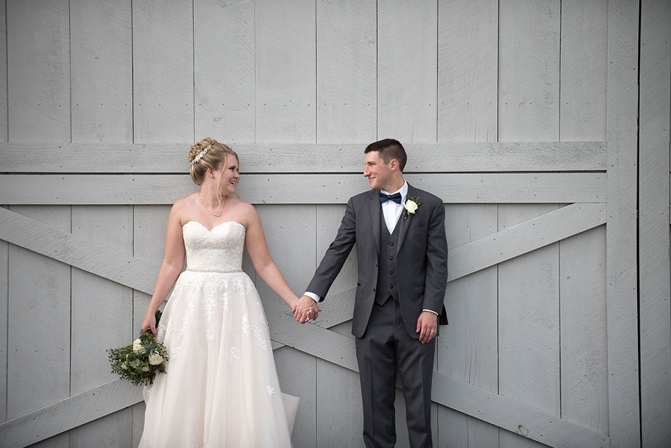 bride and groom in front of barn door