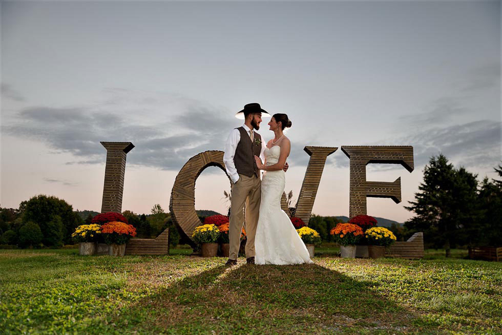 wedded couple by Love word in field