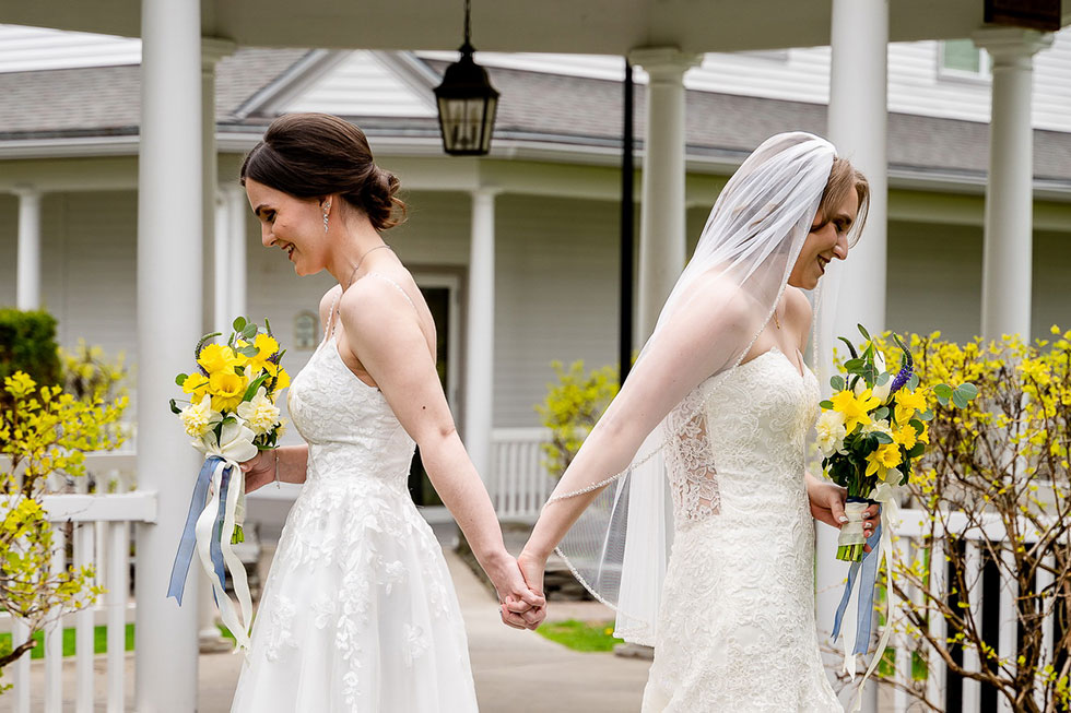two brides back to back holding hands