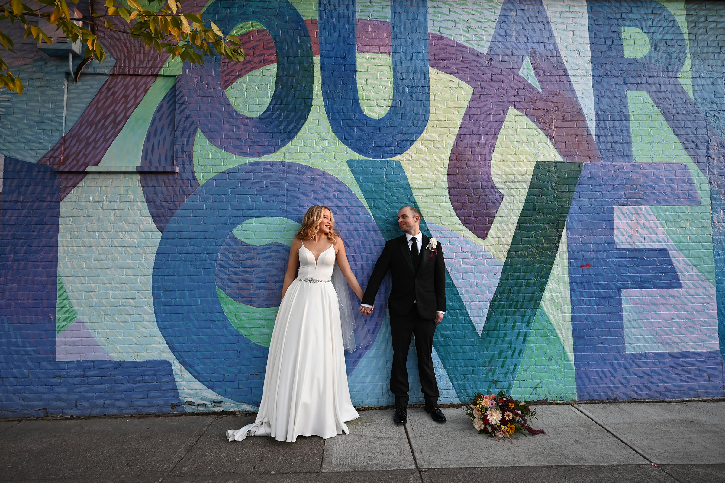 Bride and Groom in front of Love graffiti wall
