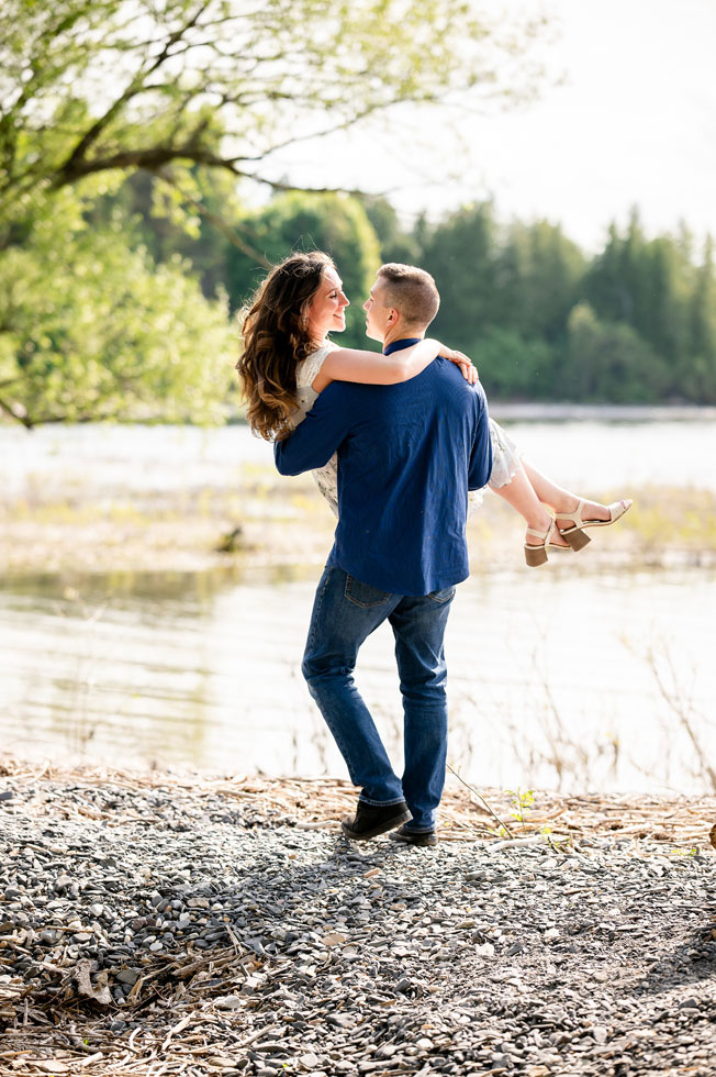 groom carrying bride near lake