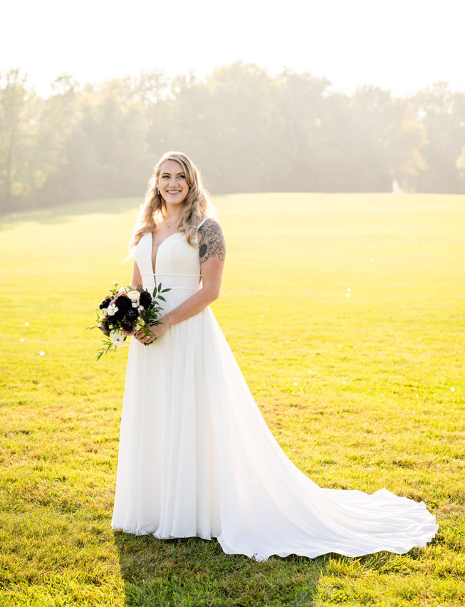 Bride posing in sunny field