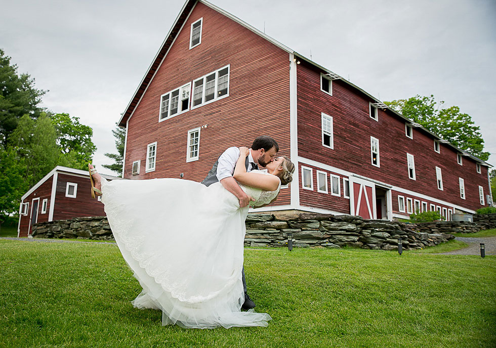 newlyweds kissing in front of barn